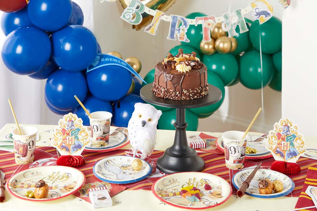 A Harry Potter-themed party with green and blue balloons showing from a Harry Potter balloon arch, a party table with Harry Potter party tab