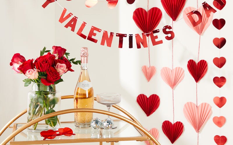 a drinks trolley with roses, champagne a glass and Valentine's day decorations behind it