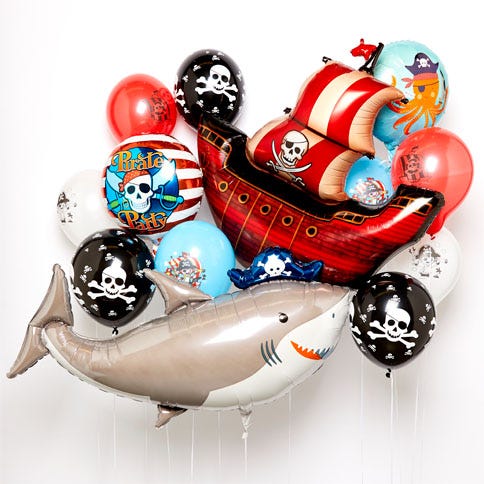 A selection of pirate-themed balloons, including skull and crossbones printed latex balloons, a large foil pirate ship balloon and a big shark balloon all on a white background.