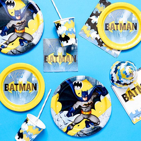 a table with batman party supplies on including plates, cups and straws featuring batman