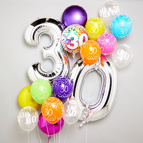 A bunch of colourful 30th birthday balloons with silver 3 and 0 balloons in the middle on a grey background