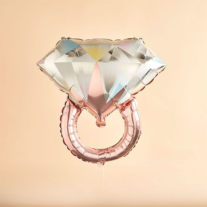 diamond ring shaped foil balloon on a plain background