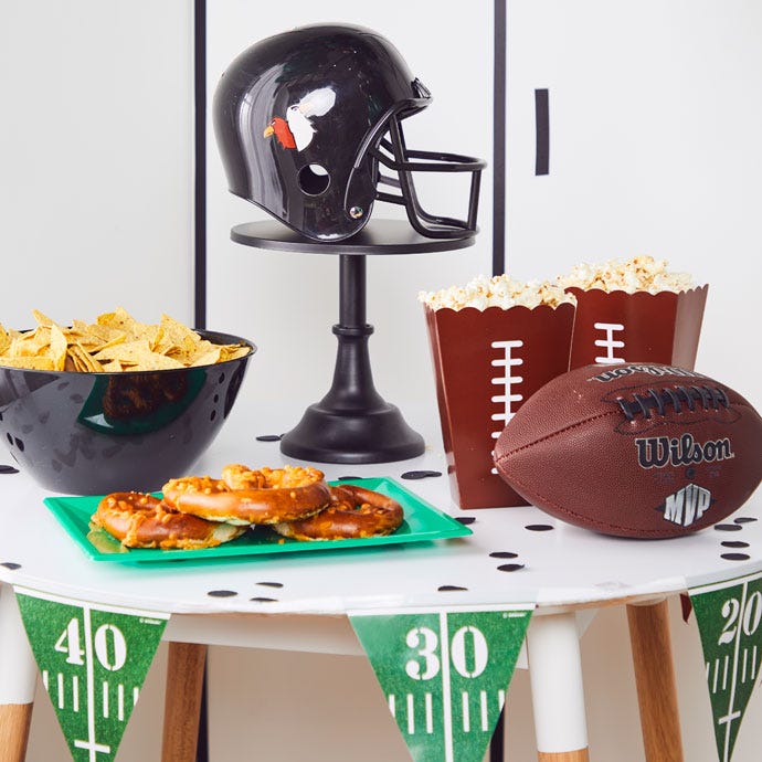 Superbowl party table with football helmet, nachos, pretzels and American football
