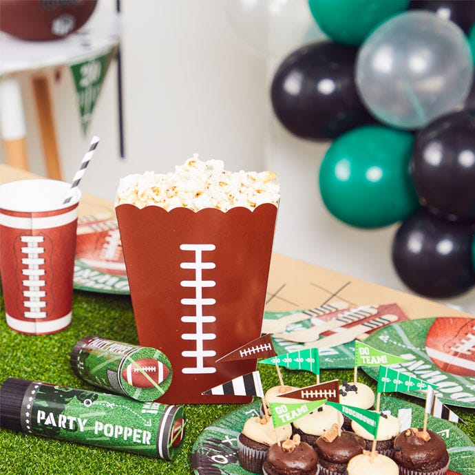 Superbowl themed party table with cake, popcorn and American Football themed plates