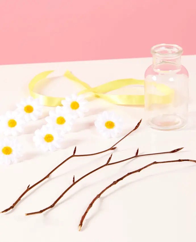 Materials for making a DIY Easter tree - sticks, flowers and an empty glass bottle