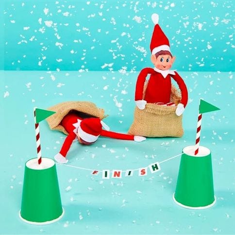 Elf on the Shelf taking part in a sack race with another elf