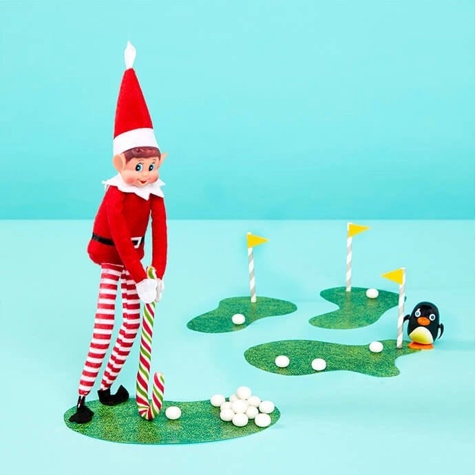 Elf on the Shelf playing golf with a candy cane