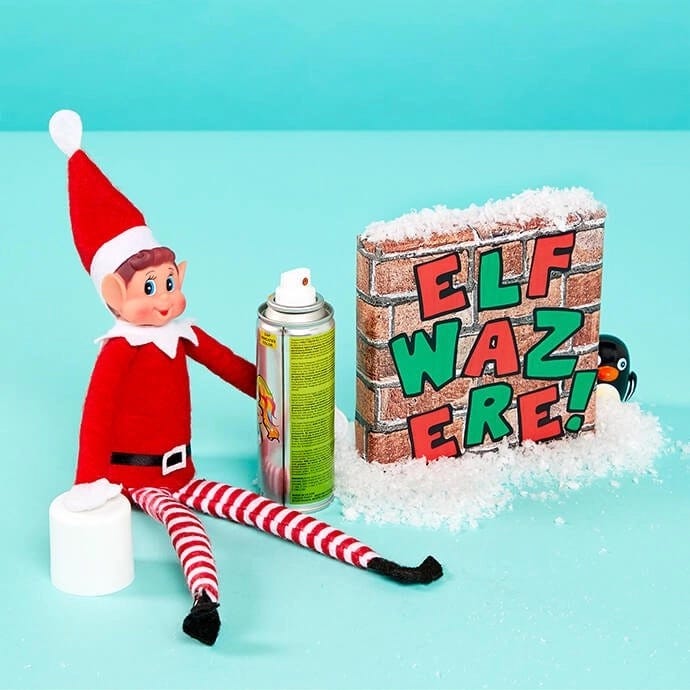 Elf on the Shelf drawing graffiti with a can of spray paint