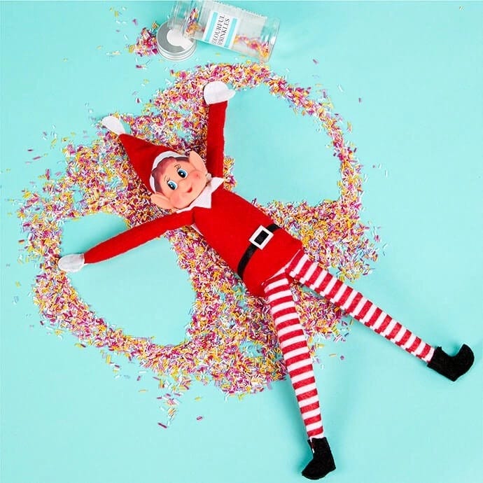 Elf on the Shelf making a snow angel with sprinkles