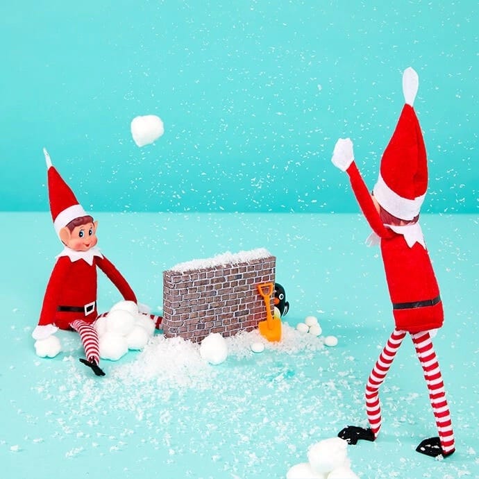 Elf on the Shelf having a snowball fight with another elf