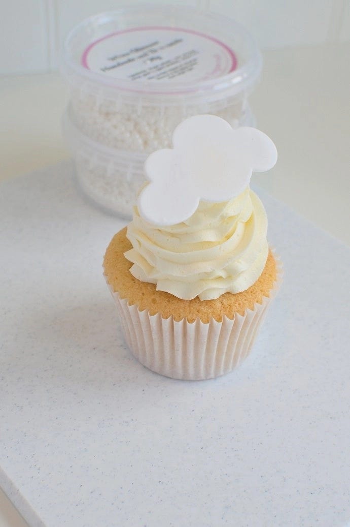 A cupcake topped with vanilla icing and a cloud cupcake topper