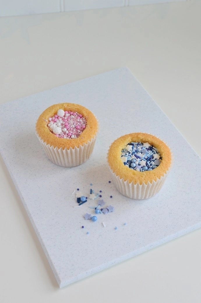 Two cupcakes filled with pink and blue sprinkles