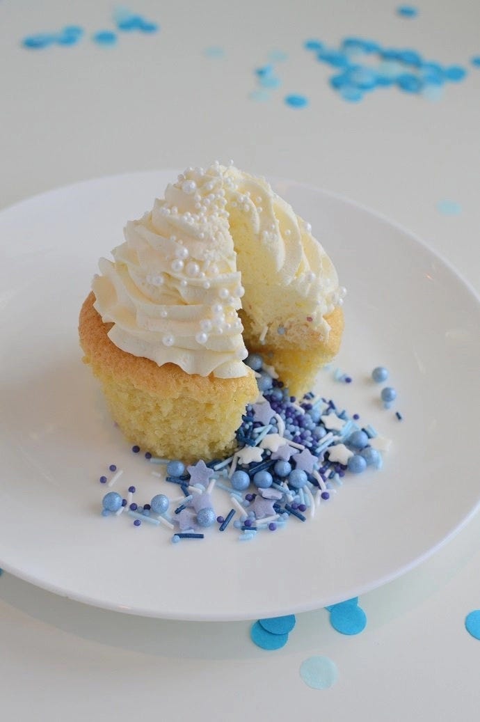 A gender reveal cupcake with blue sprinkles coming out of the middle