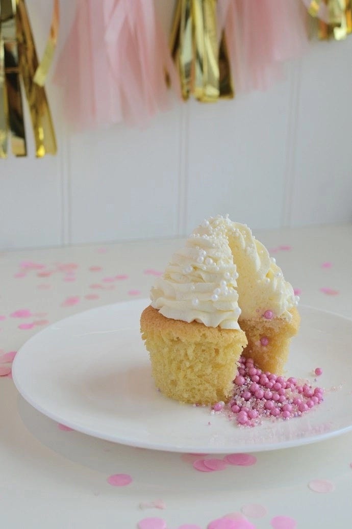 A gender reveal cupcake with pink sprinkles coming out of the middle